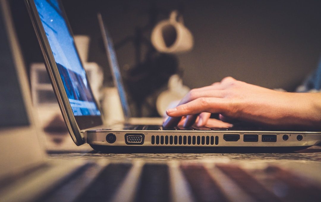 A person engaged in typing on a laptop, utilizing fax services for communication.